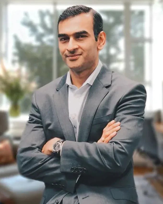 Vijai Aanand standing with his arms crossed in an office